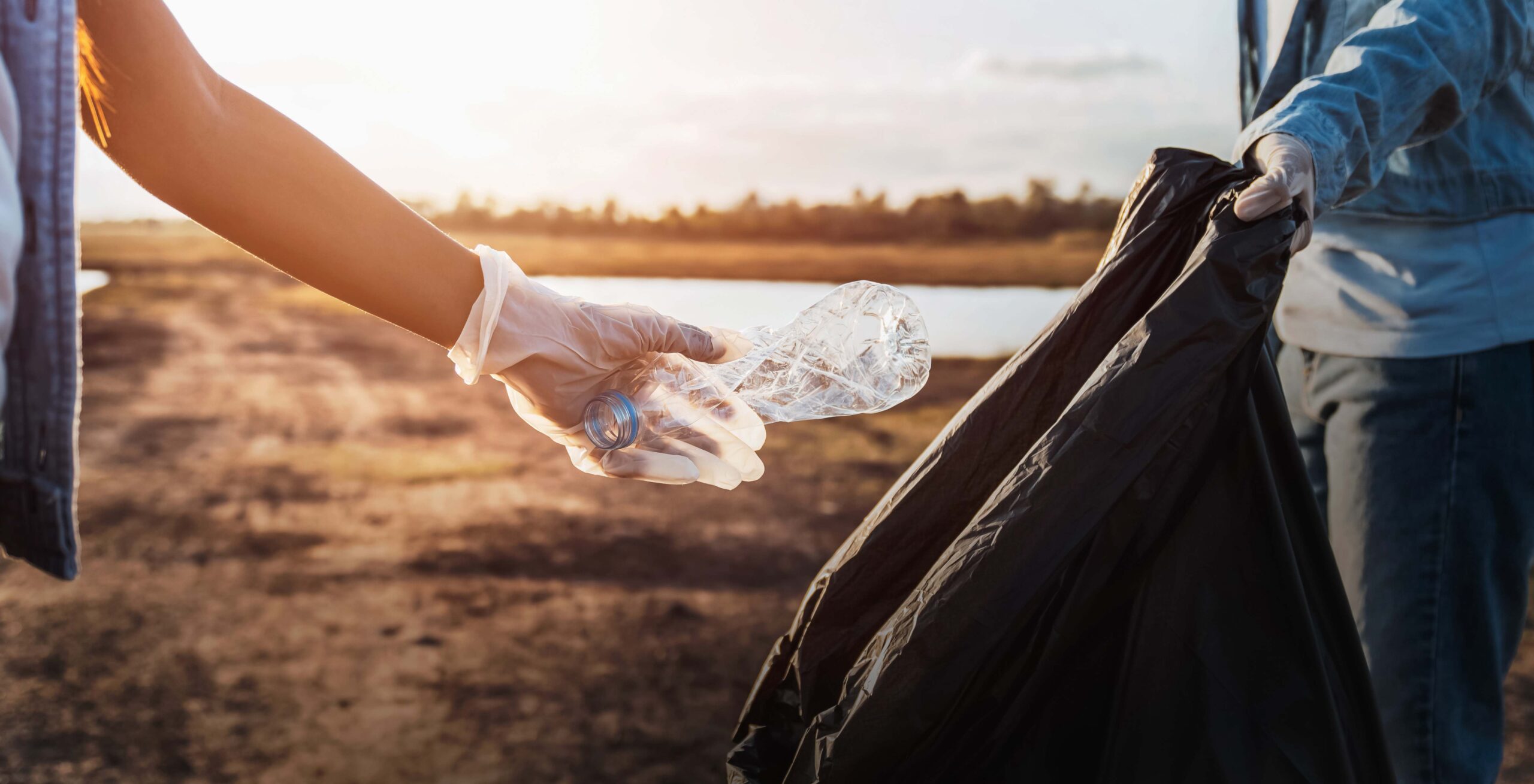 people collecting plastic bottles near the river for recycling.