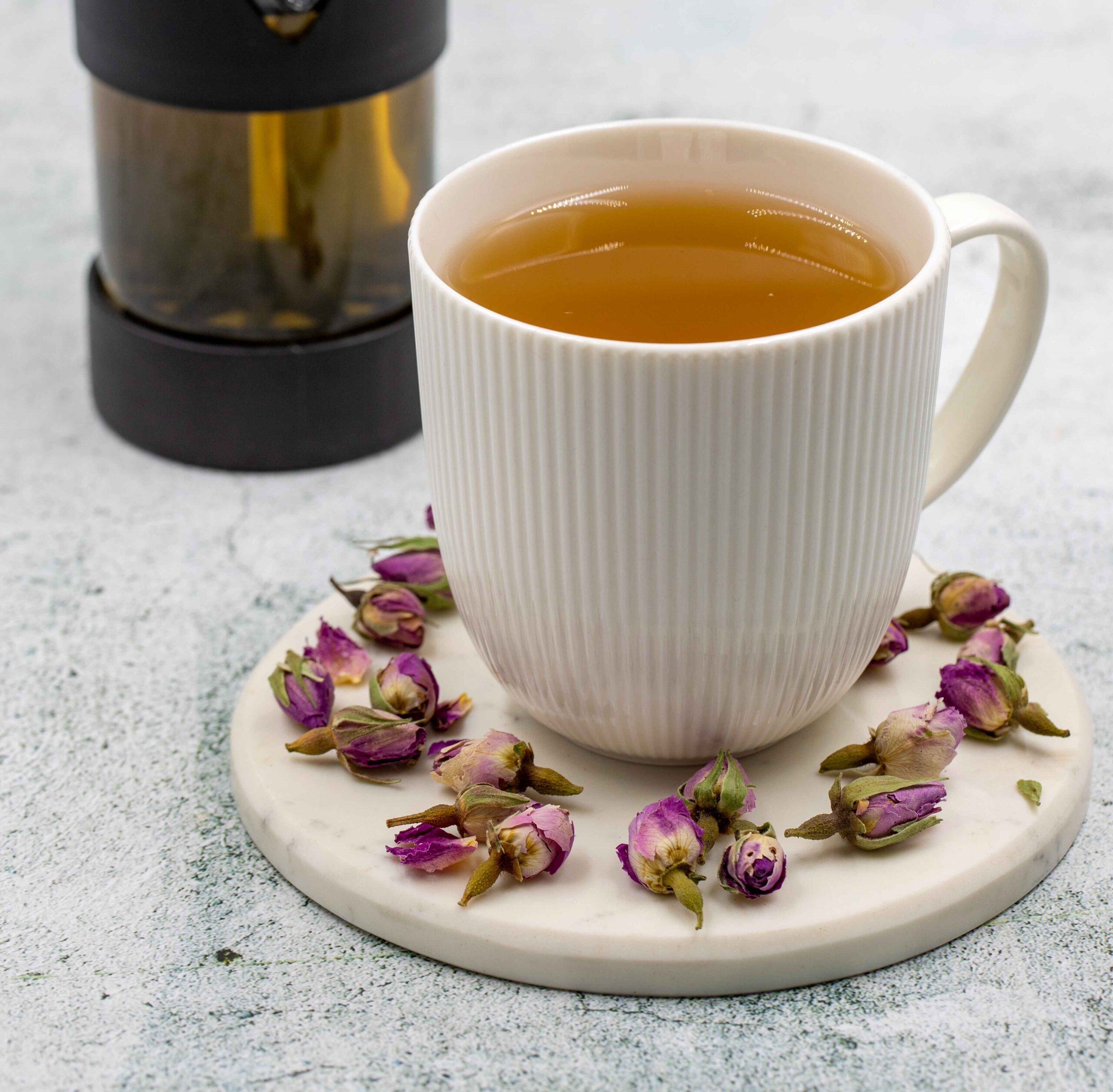 a cup of kahwa tea with rose petals placed in saucer.